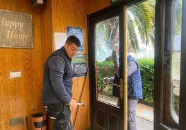 Operarios sustituyendo el cristal roto de la panadería La Artesana, donde el detenido robó la caja registradora durante la madrugada del pasado martes.