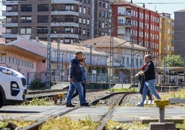 Vecinos cruzan el paso a nivel de Pablo Garnica, con la estación de Torrelavega-Centro al fondo.