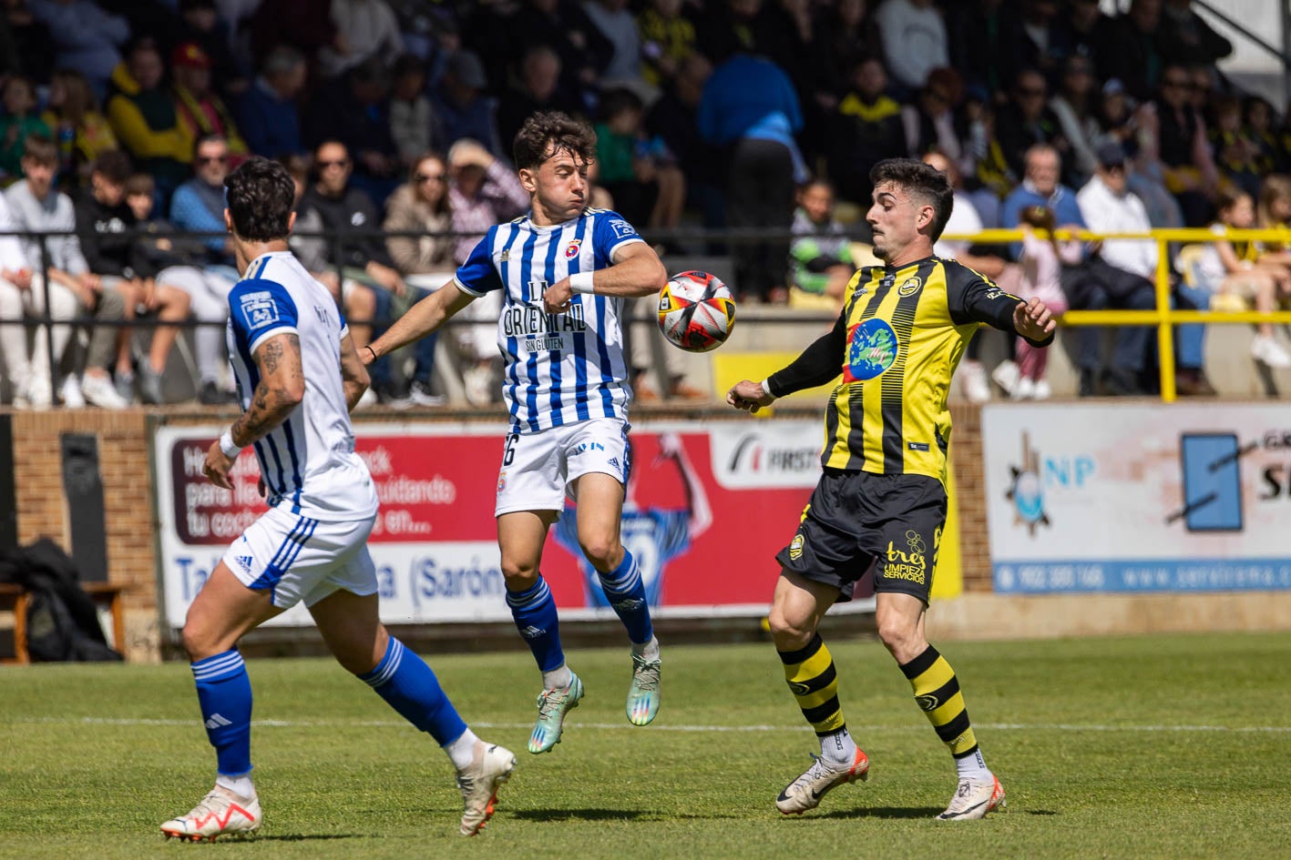 Pol Bassa, jugador de la Gimnástica, salta para pugnar por el balón con un futbolista del Cayón. 