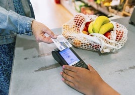 Un demandante de ayuda alimentaria paga su compra en un supermercado con la tarjeta monedero de Cáritas Diocesana.