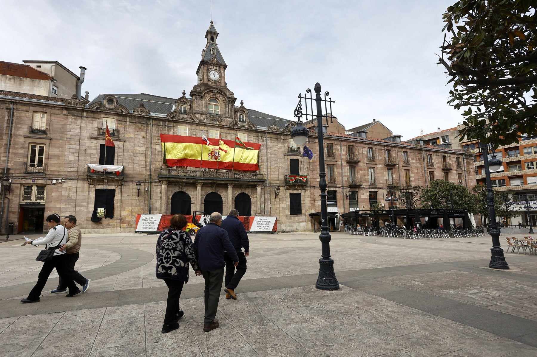 Vecinos caminan frente al Palacio municipal de Torrelavega, consolidado estructuralmente el año pasado.