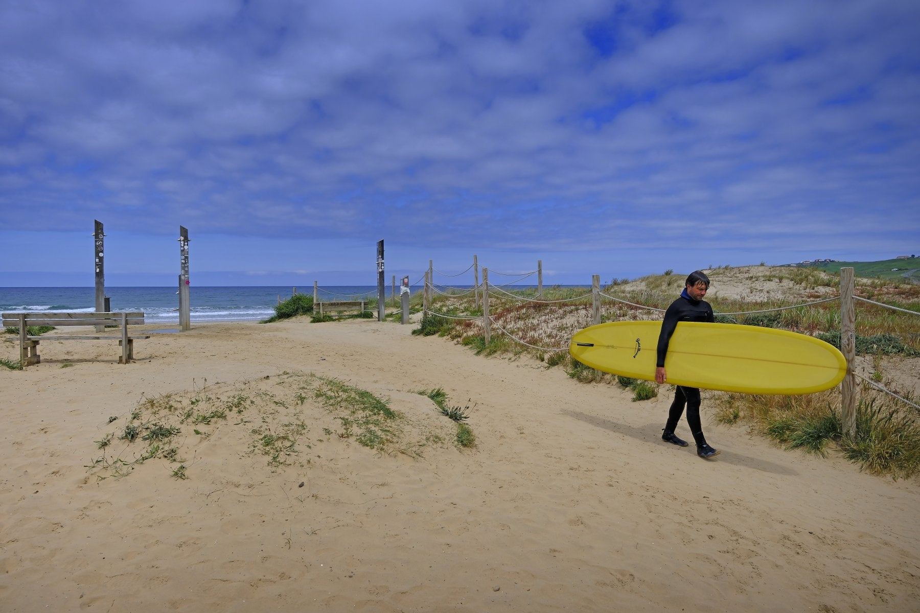 Un surfista abandona la playa de El Rosal, en San Vicente de la Barquera, en un día soleado.