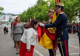 Una mujer besa la bandera de España que sujeta un Guardia Real.