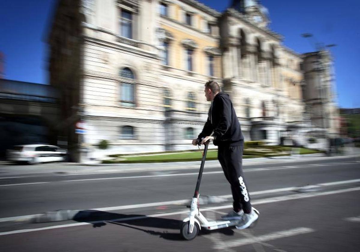 Un hombre circula en patinete por una calle.