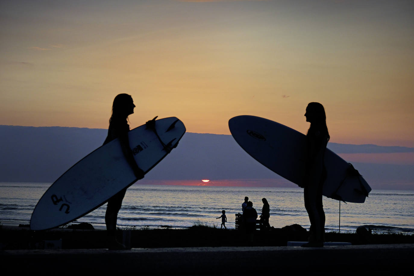 Surfistas al atardecer, en la playa de Oyambre.