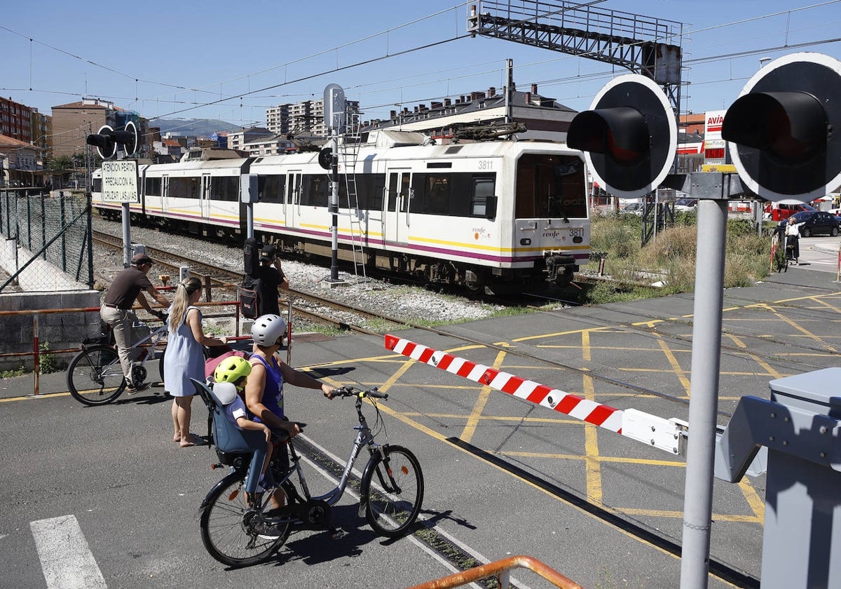 Un tren abandona Torrelavega en dirección a Santander, mientras los vecinos aguardan en el paso a nivel de Pablo Garnica.