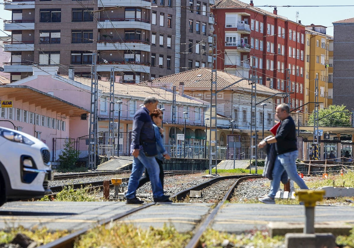 Vecinos camina por el paso a nivel de Pablo Garnica, con al estación Torrelavega-Centro al fondo, en Torrelavega.