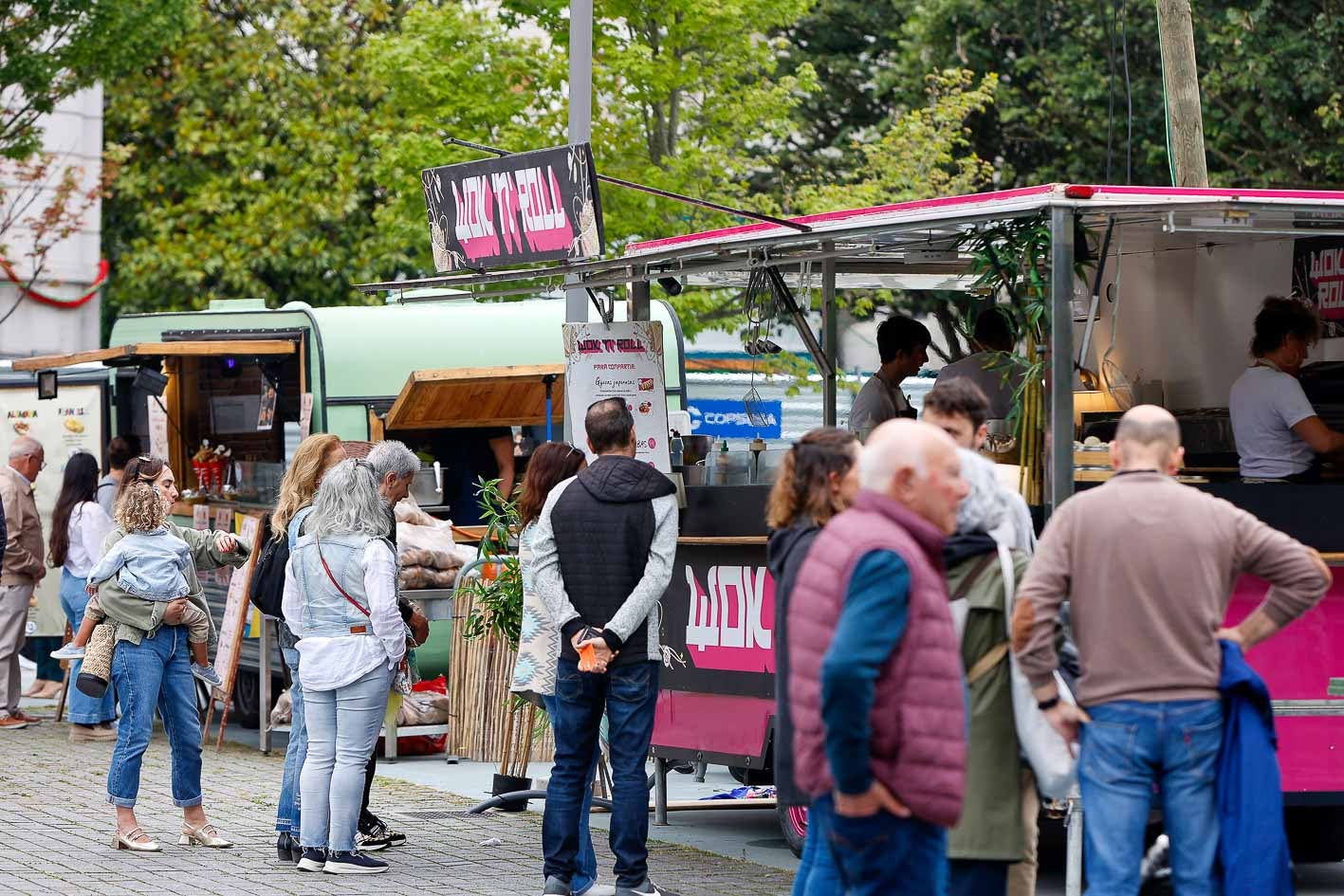 Los clientes curiosean los productos de las diferentes food trucks y hacen cola para pedir.