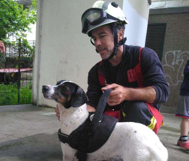 Uno de los bomberos del 112 con el perro rescatado, que presentaba pequeñas heridas.