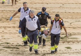 Profesionales del equipo del 061 y un policía trasladan a un paciente indispuesto en la playa.