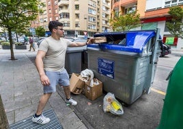 Un vecino echa cartón en un contenedor azul de Camargo.