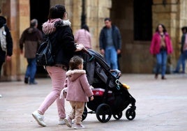 Una mujer pasea con una niña pequeña y un bebé.