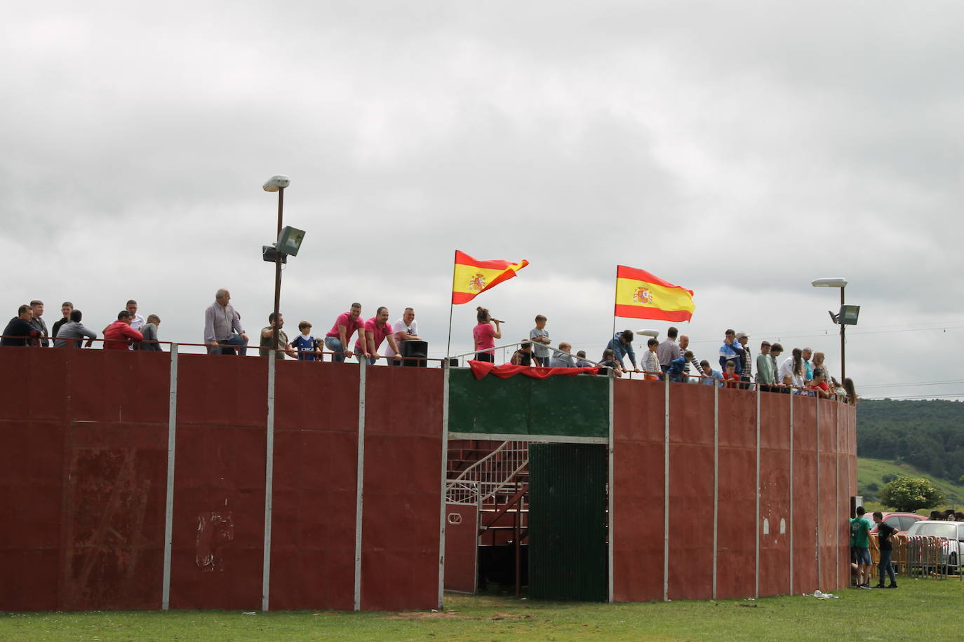 Los espectadores aprovechan la altura de la plaza de toros portátil instalada en la campa.