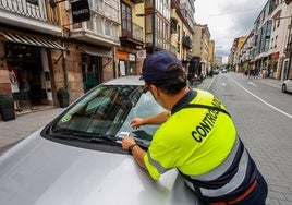 Un controlador coloca una sanción en un vehículo, ayer, en un aparcamiento afectado por la ERA en la calle Julián Ceballos.