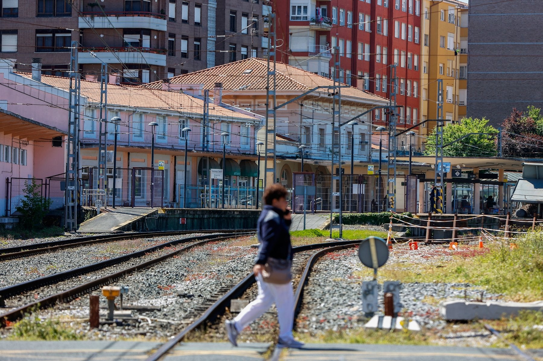 Una vecina cruza el paso a nivel de Pablo Garnica, con la estación ferroviaria Torrelavega-Centro al fondo.