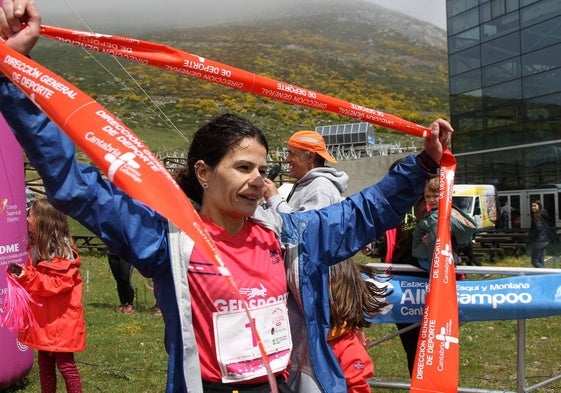 Carmen Rosa Pérez sostiene con orgullo la cinta de ganadora a su llegada a meta.