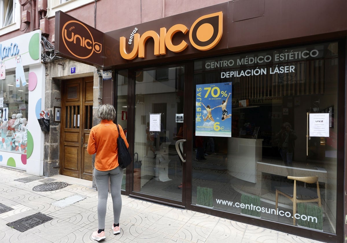 Una mujer observa el cartel del local cerrado en Torrelavega.