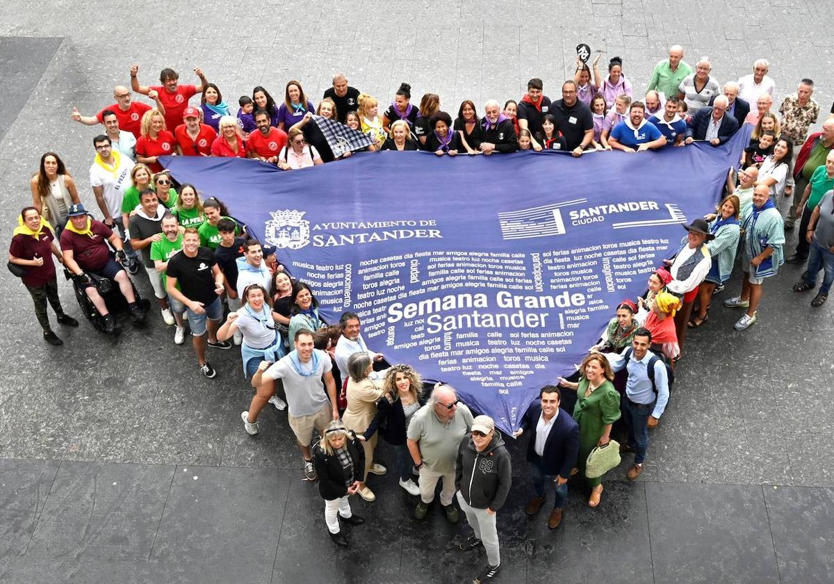 Organizadores de la programación sostienen el pañuelo de las fiestas en la plaza del Ayuntamiento.