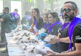 Socios de la peña Los Chatos reparten los platos de panceta y chorizo.