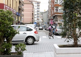 Un coche circula por la calle Julián Ceballos, mientras un ciclista gira hacia la calle Alonso Astúlez, en Torrelavega.