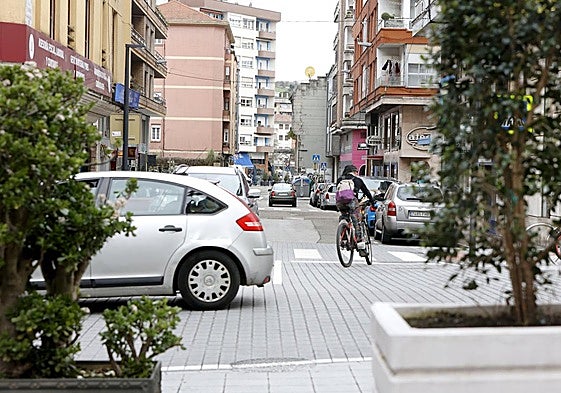 Un coche circula por la calle Julián Ceballos, mientras un ciclista gira hacia la calle Alonso Astúlez, en Torrelavega.