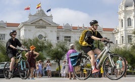 Dos turistas montan en bicicleta por el carril bici del Sardinero.