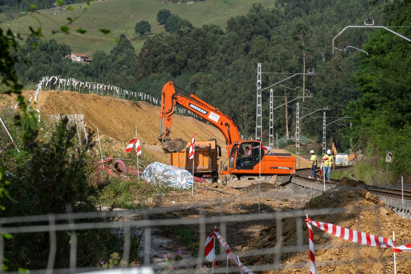 Una máquina excavadora carga de tierra un camión en las obras de duplicación de la línea férrea en Parbayón