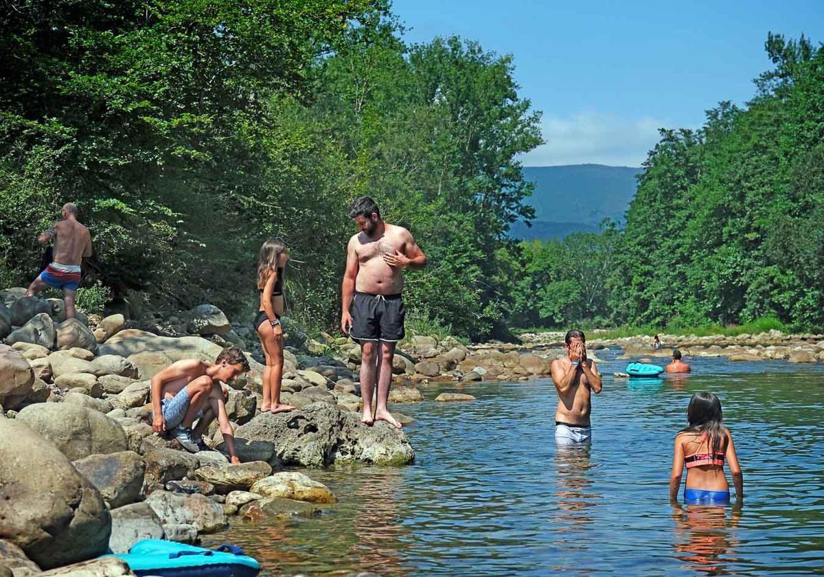 Chapuzón refrescante en el Pozo Colorado, en el río Saja, que se ha llenado este sábado de bañistas.