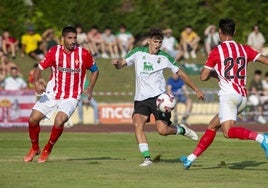 Pablo Rodríguez controla la pelota ante dos jugadores del Sporting