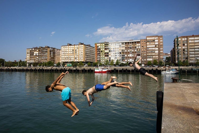 Unos chavales se tiran al agua en el Barrio Pesquero de Santander, donde el calor sigue apretando a estas horas.