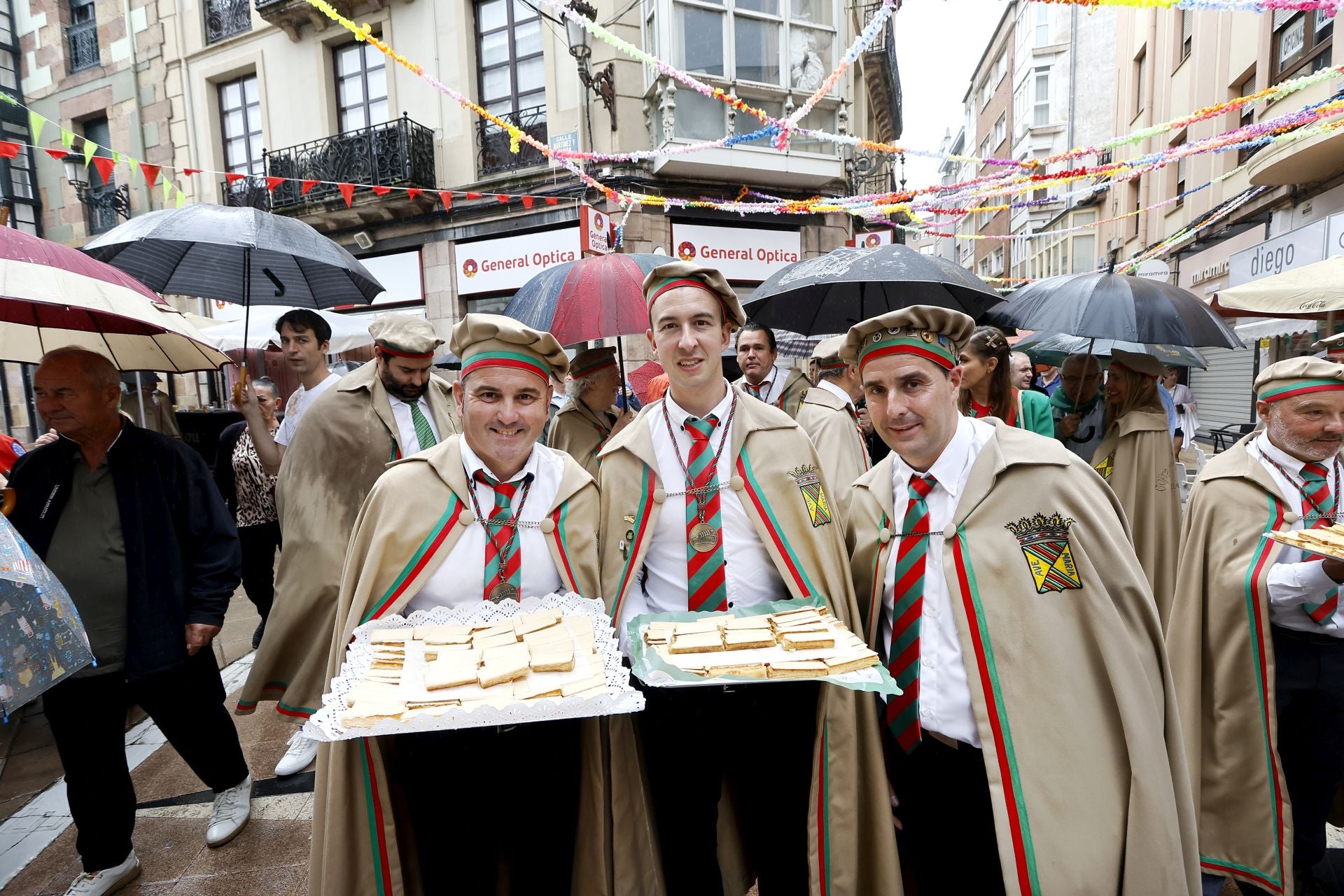 Cofrades muestran dos de las bandejas repletas de polkas, al inicio del recorrido por el centro de Torrelavega.