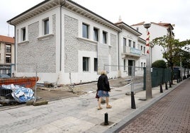 Una vecina camina junto al edificio de La Llama, que continúa en obras, esta semana, en Torrelavega.