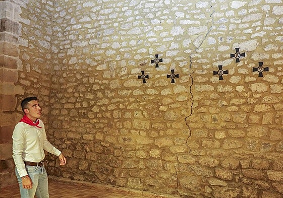 El joven vecino Raúl Roiz observa las grietas que atraviesan los muros del interior de la iglesia.