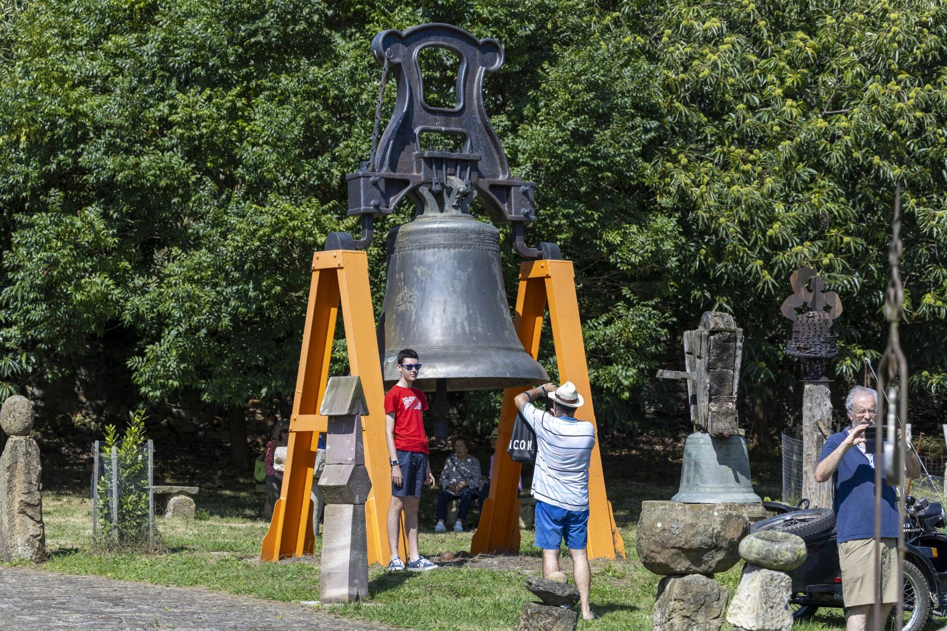 Dos aficionados se fotografían frente junto a una de las enormes campanas que se exhiben en la finca de San Bartolomé de Vierna.