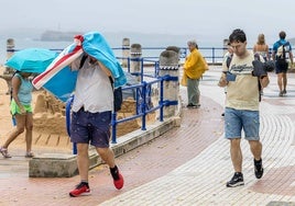 Bañistas utilizan la toalla de la playa para resguardarse de la lluvia