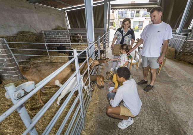 Los niños acarician a las cabras y, al fondo, Ramón Crespo y Cristina Lavín.