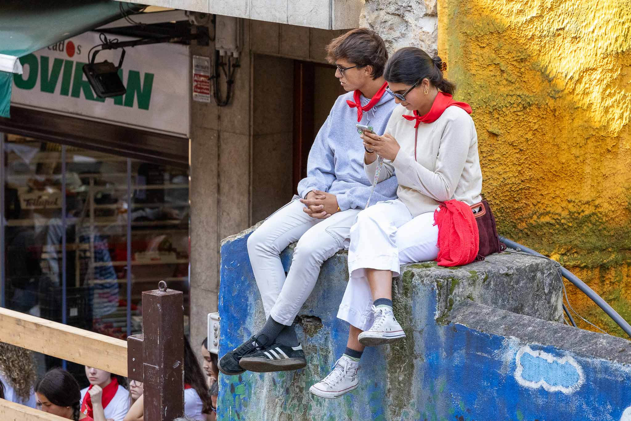 Dos jóvenes consultan el móvil en un sitio privilegiado para disfrutar del encierro. 