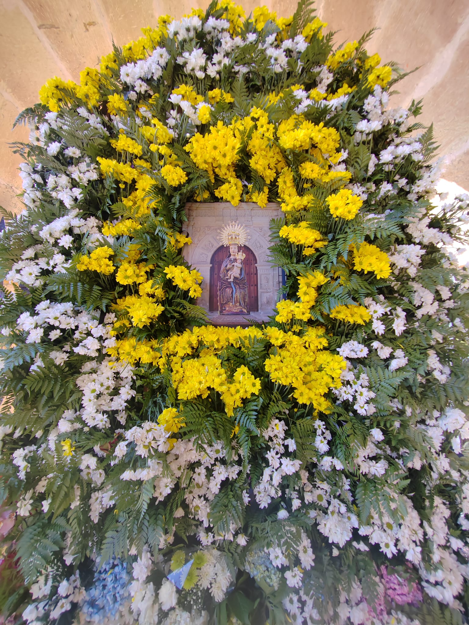 La talla de la Virgen de Valencia engalanada con un manto de flores desde el pasado sábado lució así en el Santuario de Vioño. 