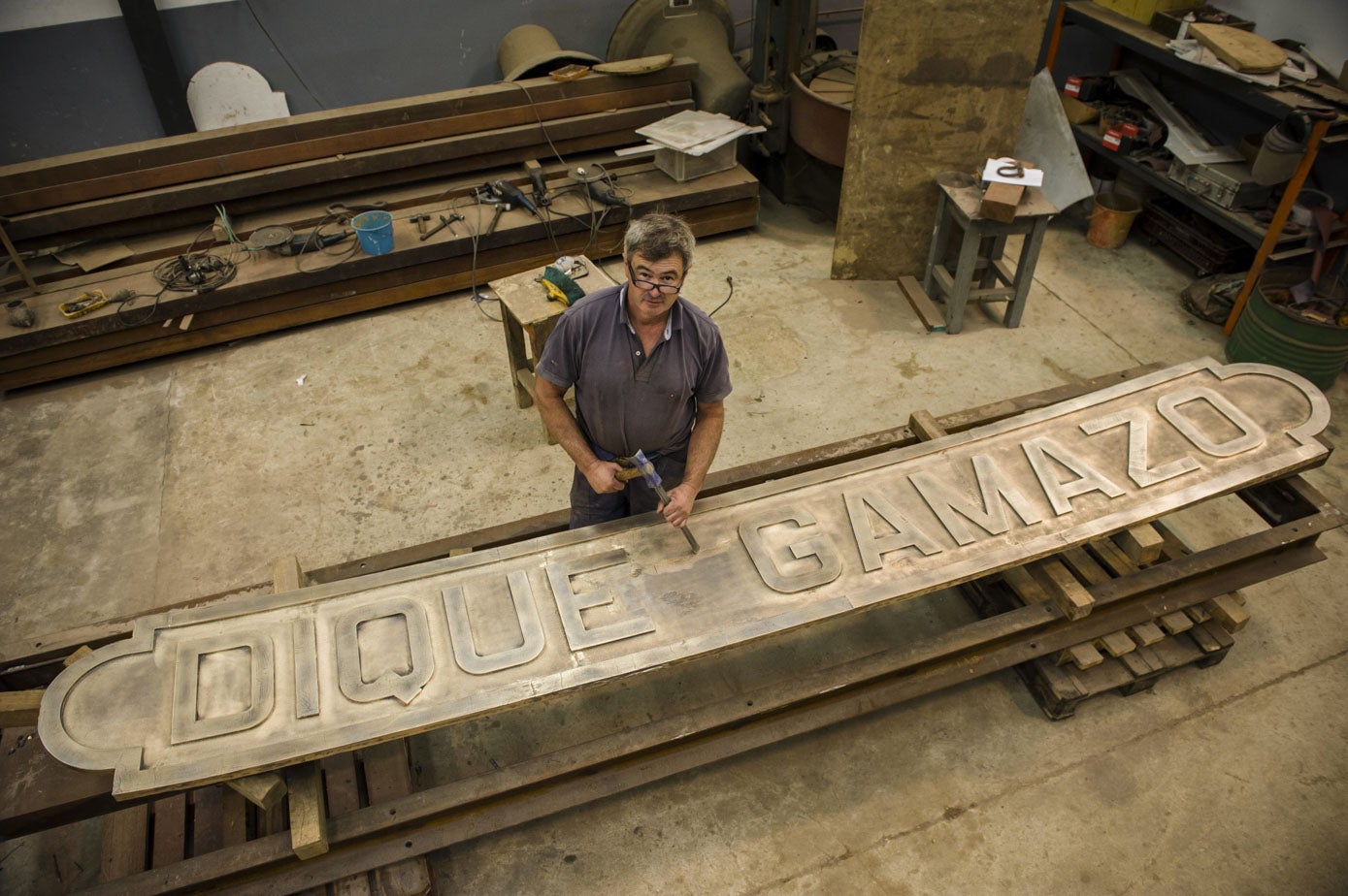 El campanero Andrés Portilla, en su taller de Gajano, trabajando en la nueva placa de bronce que se colocó en el dique de Gamazo.