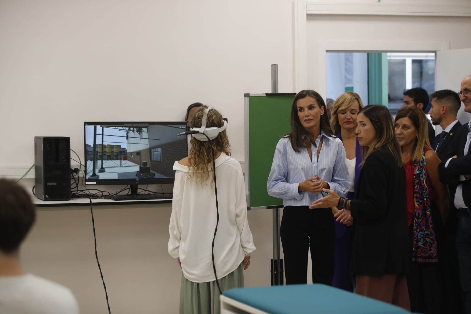 La Reina, con la ministra y la presidenta de Cantabria, siguen algunas de las explicaciones de los alumnos en una clase práctica.