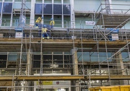 Los trabajadores retiran el recubrimiento de cristal de la fachada principal del edificio de Ministerios, en la calle Vargas.