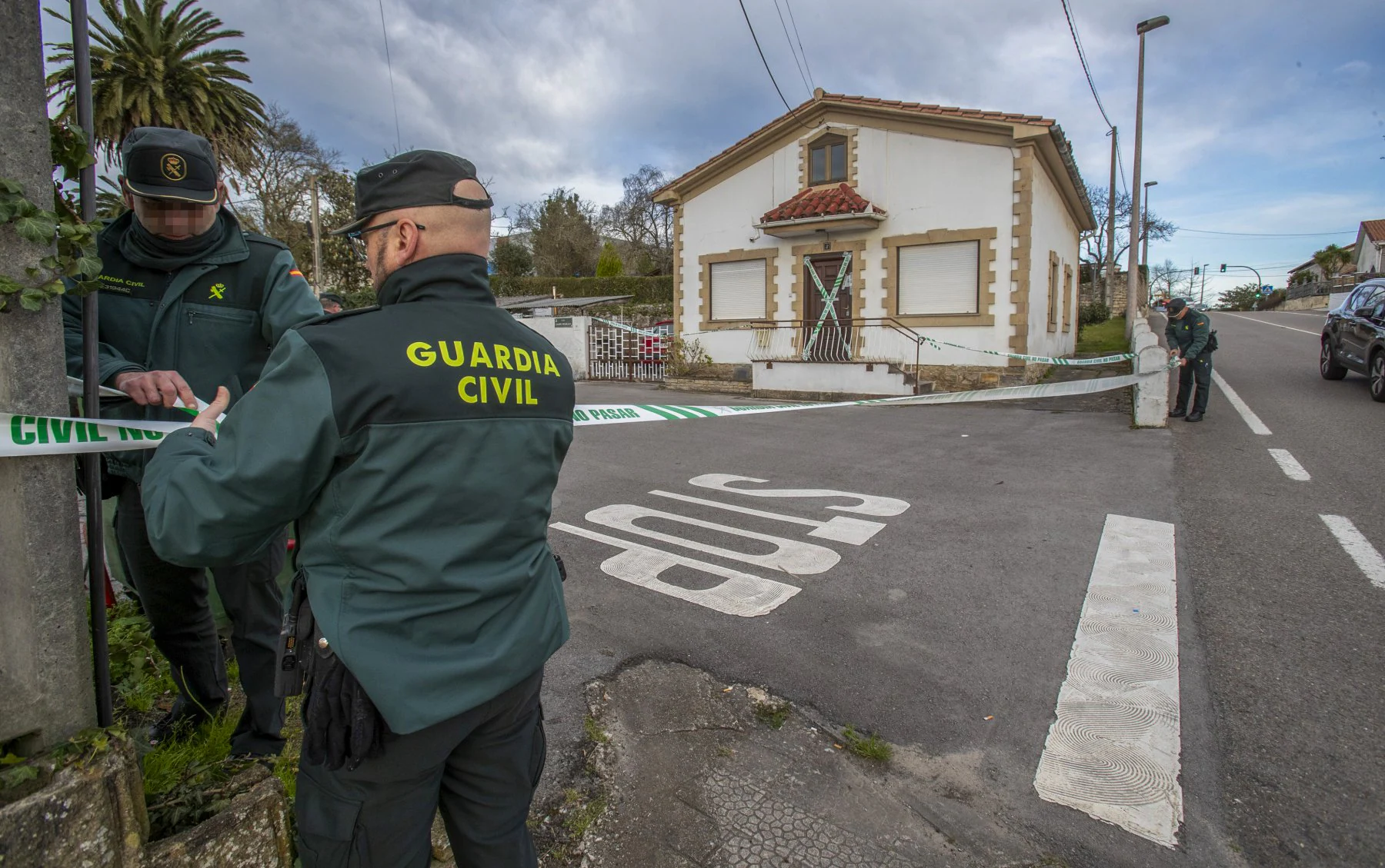 Dos agentes de la Guardia Civil acordonan una vivienda en Hinojedo donde apareció muerta una mujer.