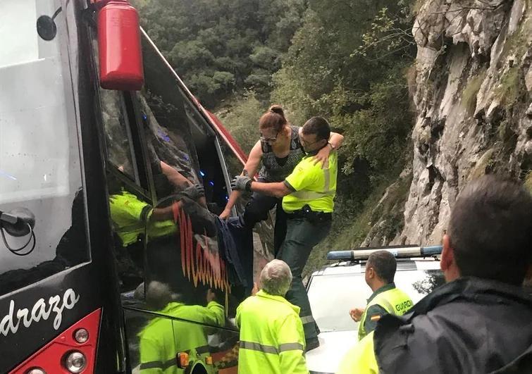 Un guardia Civil ayuda a salir a una de las pasajeras