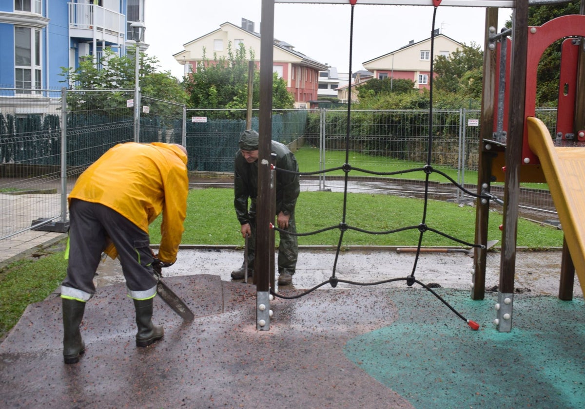 Dos operarios realizan labores de mejora en el parque infantil.