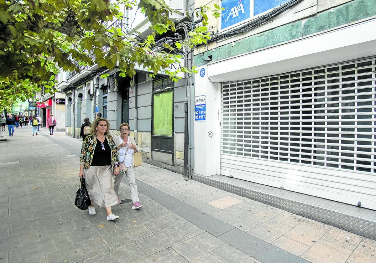 Dos mujeres pasean por delante de tres negocios cerrados en la calle San Fernando.