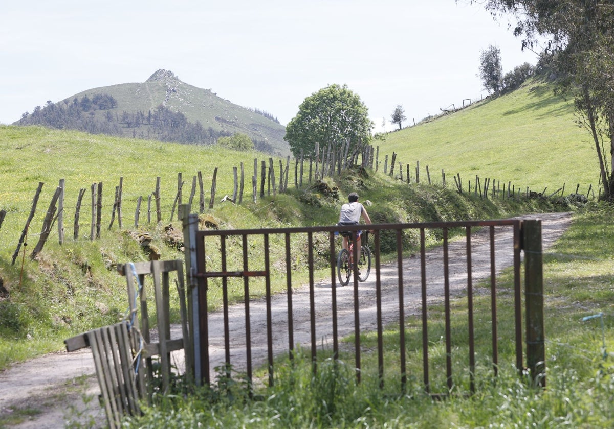 Un ciclista circula por la sierra del Dobra con el pico de La Capía al fondo.