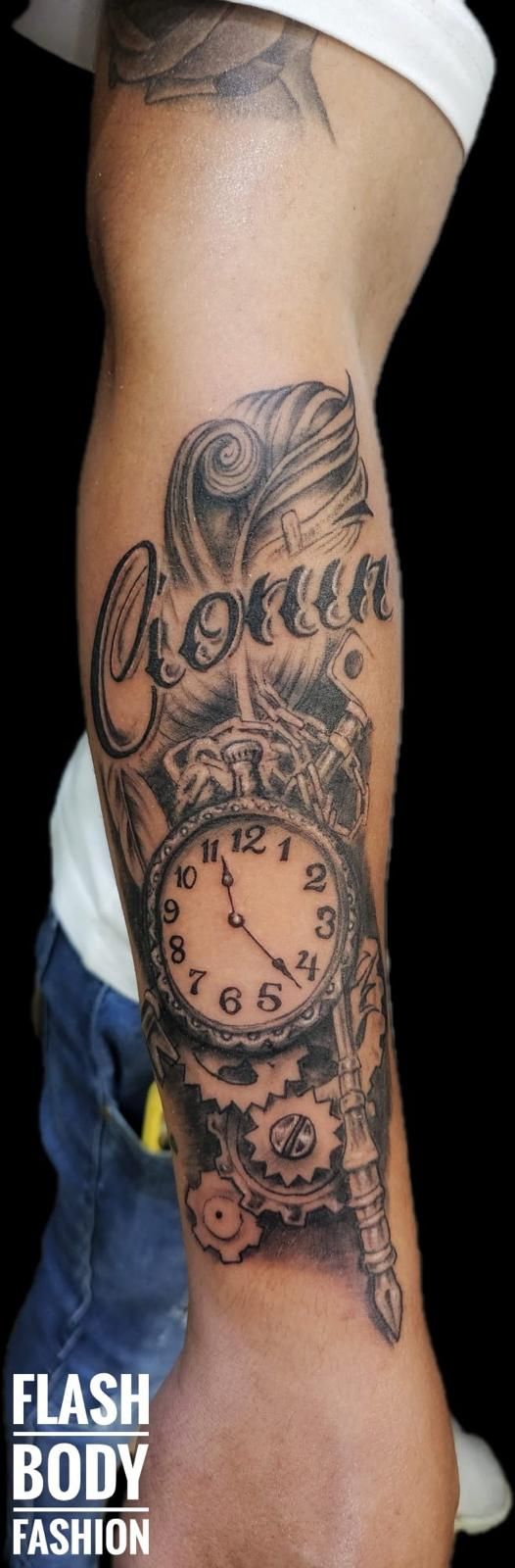 Tatuaje realizado por David Pico, que cuenta con un nombre y un reloj, además de otros detalles 