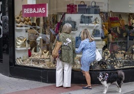 Dos mujer observan el escaparate de una tienda en Santander.