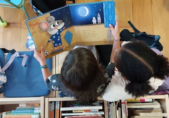 Dos pequeñas leyendo un cuento en la biblioteca.