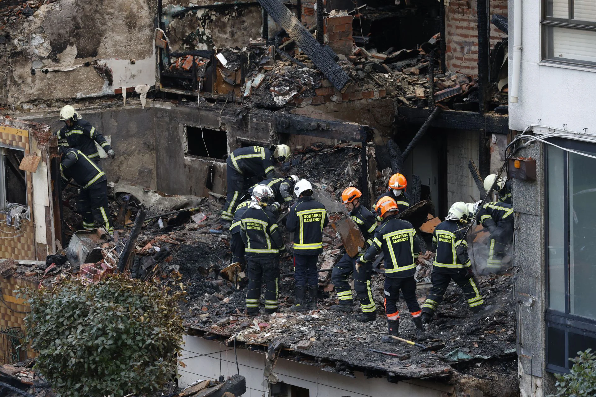 Los bomberos trabajan sobre los restos del edificio buscando a los desaparecidos